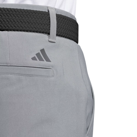 Close-up of Adidas Ultimate365 Mens Golf Pants with a back pocket, black woven belt, and Adidas logo above the pocket. The moisture-wicking pants are styled with a tucked-in white shirt for a clean golf look.