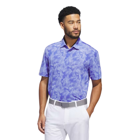 A man stands against a white background, wearing an Adidas Ultimate365 Mesh Print Mens Polo (2XL only) in blue and white, paired with white pants and a gray belt, one hand in his pocket as he looks to the side.