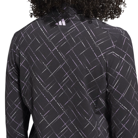 A person with curly hair wearing an Adidas Ultimate365 Printed Quarter-Zip Long-Sleeve Polo Shirt in Black/Powder Plum.