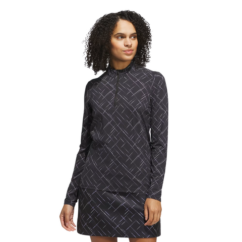 A woman with curly hair wears the Adidas Ultimate365 Printed Quarter-Zip Long-Sleeve Polo Shirt in Black/Powder Plum, standing against a plain white background.