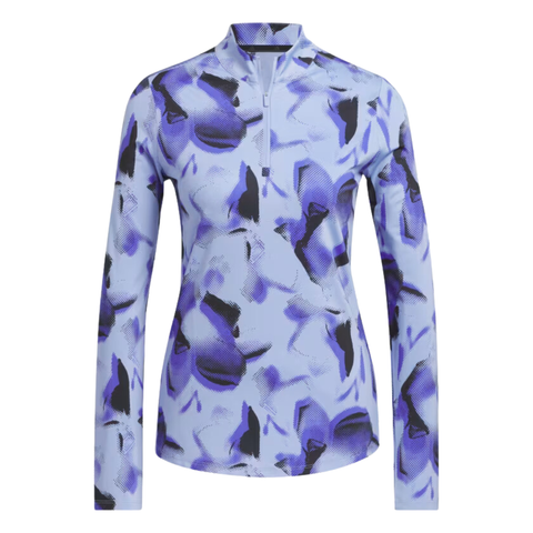 The Adidas Ultimate365 Women's Long Sleeve Golf Shirt in Blue Spark features an abstract print in shades of blue and black on a light blue background. The shirt has a zippered collar and long sleeves.