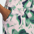 Close-up of a medium-brown hand in the pocket of an Adidas Ultimate365 Womens Skort by Adidas, featuring an abstract green, navy, and light pink pattern.