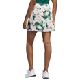 A person faces away from the camera, wearing a green top, white sneakers, and the Adidas Ultimate365 Womens Skort by Adidas in pink and green pattern, all set against a white background.