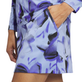 A person wearing the Adidas Ultimate365 Womens Skort by Adidas, shown from waist to mid-thigh, features a light blue and purple abstract pattern with black accents and has their right hand in the pocket.