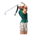 A woman in a green sleeveless top, the Adidas Ultimate365 Women's Skort by Adidas, and a white cap swings a golf club as she follows through on her shot.