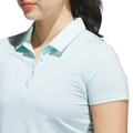 A woman is shown from the shoulders up against a white background, wearing an Adidas Women's Ottoman Short Sleeve Polo Shirt in Flash Aqua, featuring thin white stripes and breathable Ottoman fabric.