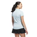 A woman with a ponytail, smiling and facing away, models the Adidas Women's Ottoman Short Sleeve Polo Shirt in Flash Aqua with breathable fabric, paired with a black skirt.