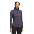 A woman wears the Adidas Women's Ultimate365 Long Sleeve Shirt, featuring a purple geometric pattern and UV 50+ fabric, with black pants, standing against a plain white background.