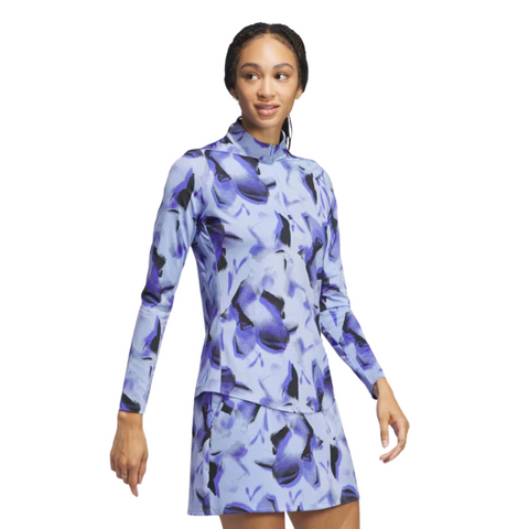 A woman stands against a white background, looking to the side, wearing the Adidas Women's Ultimate365 Long Sleeve Shirt featuring a blue and purple abstract pattern.