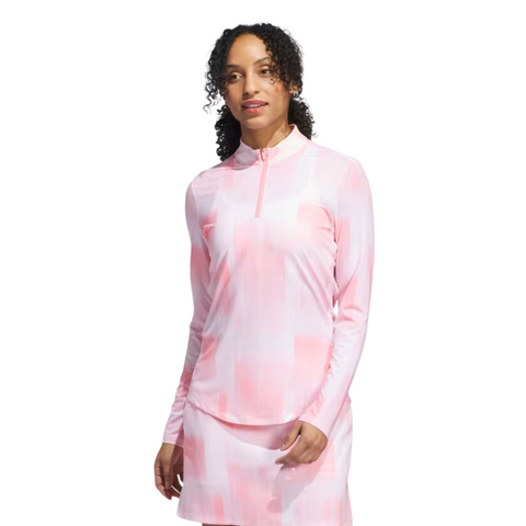 A woman with curly hair wears the Adidas Women's Ultimate365 Long Sleeve Shirt and a matching skirt, standing facing forward against a white background.