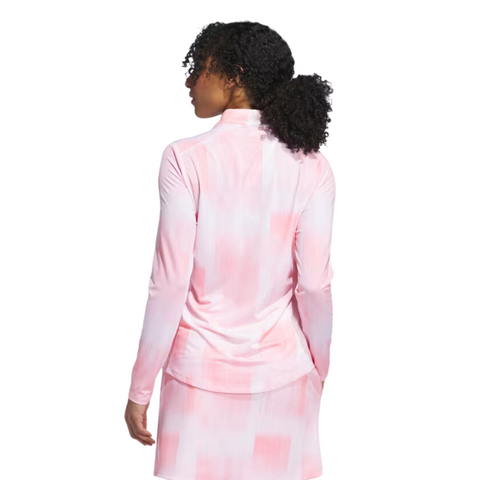 The Adidas Ultimate365 Women's Long Sleeve Golf Shirt in White Pink, worn by a model, features a soft pink and white gradient pattern, shown from the back with long sleeves and a mock neck.