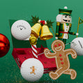 A festive scene features Callaway 2025 Supersoft 12-Day Advent Calendar Golf Balls by Callaway, surrounded by a gingerbread man cookie, golden jingle bells, a red ornament, and a nutcracker figurine against a green background.