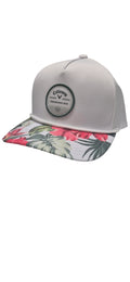 The Callaway Bogey Free Cap by Callaway is a light gray golf cap with a round front logo patch and a flat brim that features a vibrant tropical floral pattern in pink, green, and red.