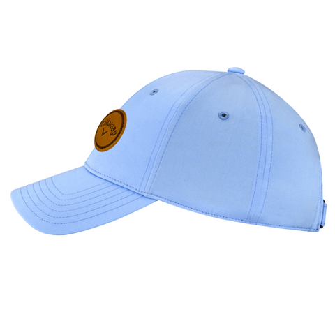 The Callaway Women’s Heritage Twill Golf Cap features a light blue design, curved brim, side round brown Callaway logo patch, stitched eyelets and details, sun protection, and an adjustable fit.