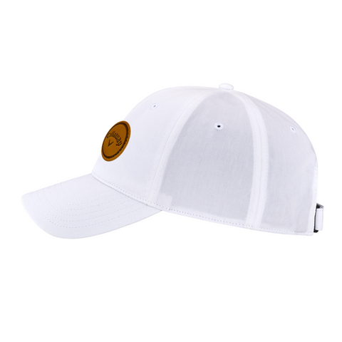 The Callaway Women’s Heritage Twill Golf Cap features a curved bill for sun protection, a round brown side patch with logo and text, stitched panels, ventilation eyelets, and an adjustable fit for all-day comfort.