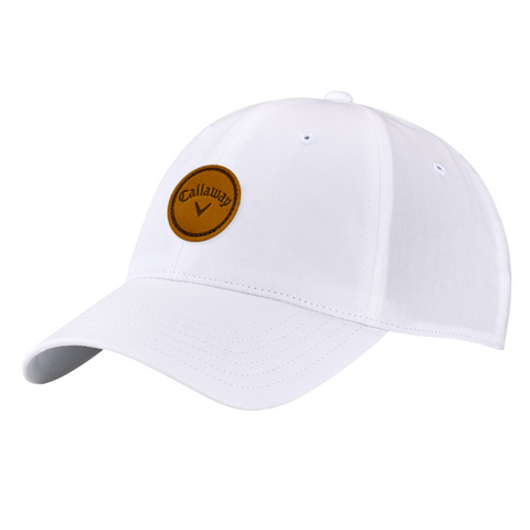 The Callaway Women’s Heritage Twill Golf Cap is a white cap with a curved brim, brown circular logo patch on the front, and an adjustable fit for comfort and sun protection.