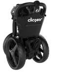 Folded Clicgear Model 4 golf trundler in black, showcasing its compact size with prominent 'Clicgear' and 'Model 4' logos visible. Stands vertically for space saving.