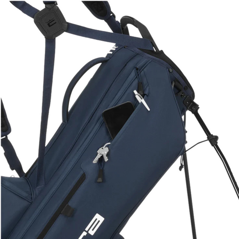 A close-up of a navy blue Cobra 2025 Ultralite Pro Stand Bag with a partially open zippered pocket revealing a black smartphone. This lightweight golf bag has white lettering and black straps.