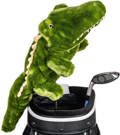 A plush green alligator golf driver headcover from Daphne’s Animal Golf Headcovers by Daphne sits on a club in a golf bag next to a metal driver, set against a white background.