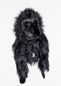 A black plush gorilla toy with long, shaggy fur lies flat on a white background, resembling a Daphnes Animal Golf Headcover by Daphne designed as an animal-themed headcover for golf clubs.
