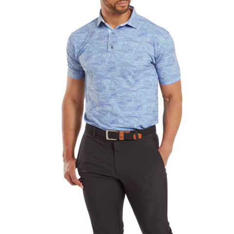Model wearing the FootJoy Golf Doodle Polo in storm blue with abstract white and purple doodles, paired with dark pants. The polo features a button-down collar and a fitted design.