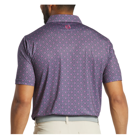A man is seen from behind wearing a purple FootJoy Flying Wasp Men’s Lisle Polo and light-colored pants. This polo by FootJoy has a repeating mini design, logo below the collar, and moisture-wicking fabric for comfort.