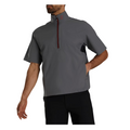 A man wears a gray FootJoy HydroLite X Short Sleeve Rain Shirt with a half-zip and high collar, paired with black pants. His left hand is in his pocket, and his face is partially out of frame.