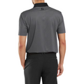 A man is shown from the back wearing a FootJoy Men's Checker Print Lisle Polo in Black/Grey with short sleeves, dark checker print, black collar, FJ logo on the back collar, and black pants. The polo is made from lightweight lisle fabric.