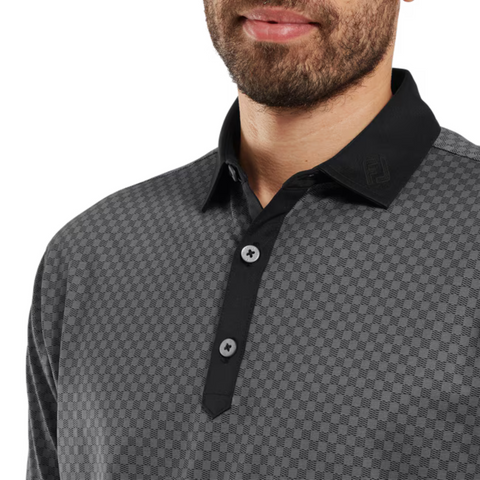 A man models the FootJoy Men's Checker Print Lisle Polo in Black/Grey, featuring a black collar and lightweight Lisle fabric. Only his lower face, neck, and upper torso appear in the image.