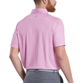 A man with a short beard, wearing a FootJoy Men’s Citrus Print Lisle Polo in Lemonade/Skyway, stands facing away. The light pink patterned golf shirt is tucked into gray pants and features a small FJ logo below the collar.