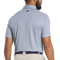 A man with a beard is seen from behind wearing a FootJoy Men’s Citrus Print Lisle Polo in White/Navy, made with ProDry fabric and featuring a small “FJ” logo beneath the collar, paired with beige pants.