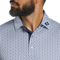 Close-up of a man with a beard wearing the FootJoy Men’s Citrus Print Lisle Polo in White/Navy, featuring a geometric pattern and blue "FJ" embroidery on the collar as he looks to the left.