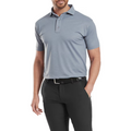 A man wears the FootJoy Men's Etched Texture Print Lisle Polo in Flint, short-sleeved and tucked into black pants with a belt, standing with one hand in his pocket against a white background.