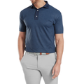 A man wearing a FootJoy Men's Etched Texture Print Lisle Polo in navy, tucked into light gray pants with a brown-buckled belt, stands with one hand in his pocket. His face is not fully visible.