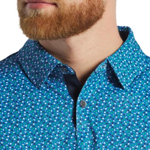 A close-up of a bearded man in a blue FootJoy Mens Geometry Print Stretch Pique Polo with a spread collar, showing only part of his face and neck.