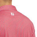 Close-up of a person wearing the FootJoy Men's Lisle Houndstooth Geo Print Polo in Hibiscus, featuring a white geometric pattern and FJ logo on the upper back.