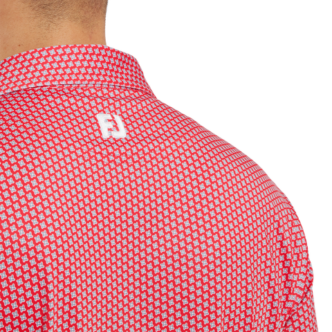 Close-up of a person wearing the FootJoy Men's Lisle Houndstooth Geo Print Polo in Hibiscus, featuring a white geometric pattern and FJ logo on the upper back.