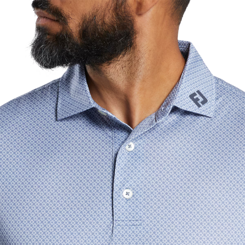 A dark-bearded man wears a collared FootJoy Men's Loop Print Lisle Polo in White/Skyway with an FJ logo, made from ProDry Moisture-Wicking fabric, his head turned slightly to the side.
