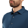A close-up shows a man in the FootJoy Mens Micro Feeder Stripe Lisle Polo - Navy/Tonal, featuring its subtle stripes and collar with his lower face, neck, and upper torso visible.