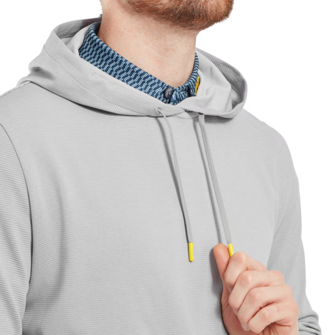 A man wears the FootJoy Men's Ottoman Jacquard Pullover Hoodie in grey, featuring yellow-tipped drawstrings, over a blue patterned collared shirt. He holds one drawstring near his chest, highlighting this athletic golf hoodie by FootJoy.