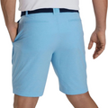 A person wearing FootJoy Mens Performance Lightweight Shorts in light blue stripes, paired with a dark blue belt and white shirt, seen from the back with a hand in their pocket. The moisture-wicking fabric helps keep them cool on the course.