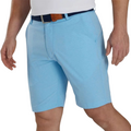 A person wears light blue FootJoy Mens Performance Lightweight Shorts with subtle stripes, front pockets, and moisture-wicking fabric, paired with a white shirt and dark belt. The look is cropped below the shoulders and at the thighs.