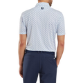 A man seen from the back wears a FootJoy Mens Pique Solid Figure Print Lisle Polo in white/navy and dark blue trousers. The moisture-wicking polo displays a small FJ logo just below the collar at the upper back.
