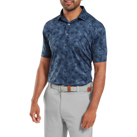 A man wearing a FootJoy Men's Pop Camo Lisle Polo in Dark Denim stands against a white background.