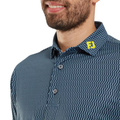 A bearded man wears a FootJoy Men’s Wiggle Print Lisle Polo in navy/white. The button-down features a ProDry Performance Fabric collar with yellow FJ initials. Only his lower face and upper torso are shown.