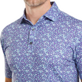 A close-up shows a man in the FootJoy Primrose Print Lisle Mens Polo, a blue and purple golf shirt featuring a collar and two buttons, with only his lower face and upper torso visible.