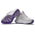 A pair of FootJoy Quantum Womens Golf Shoes in white with purple soles, featuring a spikeless tread—one shoe stands upright while the other lies on its side to show the sole pattern. Brand: FootJoy.