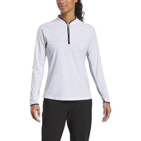A woman wears a FootJoy Women's Quarter-Zip Long Sleeve Sun Protection Shirt in white, featuring UPF 50+, and black pants, standing forward with a slight smile.