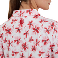 A close-up of a woman's upper back and neck wearing the FootJoy Women's 1/4 Zip Short Sleeve Floral Shirt in red/pink, featuring a floral pattern and a small red FootJoy logo embroidered below the collar.