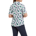 A person in a FootJoy Women's 1/4 Zip Short Sleeve Floral Shirt and dark pants stands with their back to the camera.